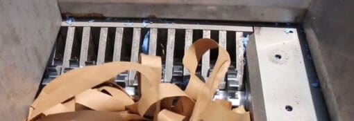 ribbons of cardboard packaging being destroyed in an industrial shredder