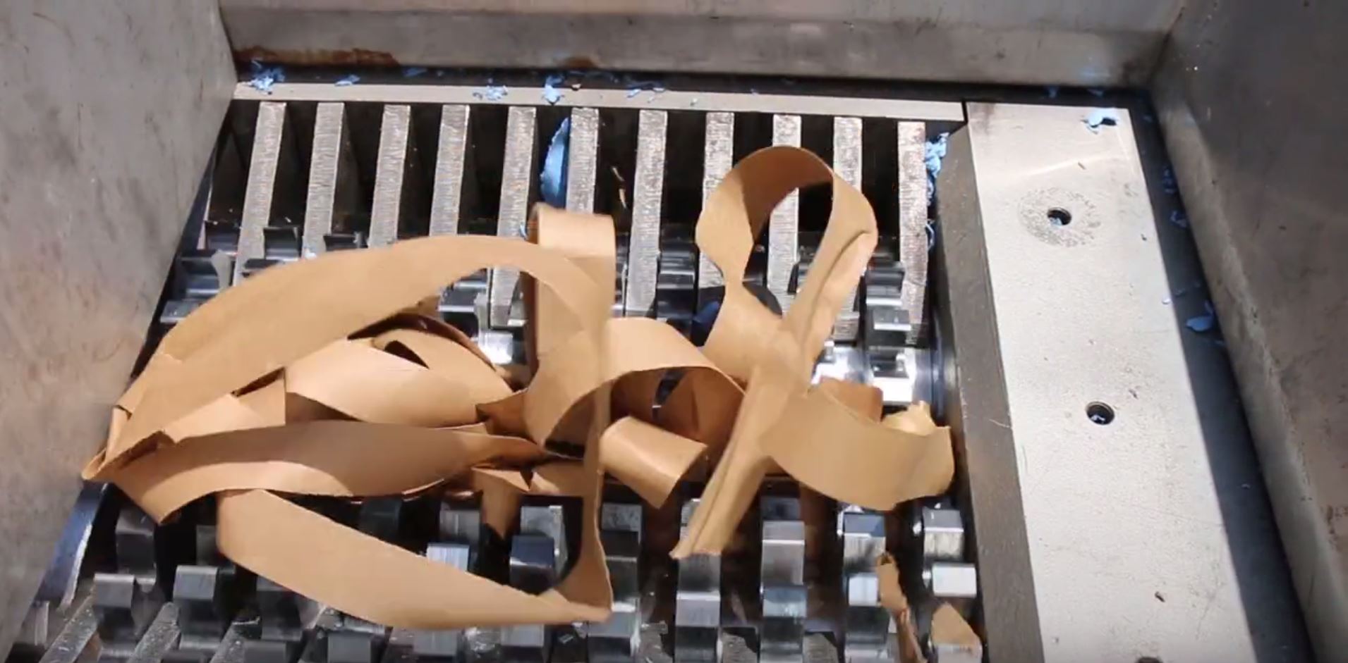 ribbons of cardboard packaging being destroyed in an industrial shredder