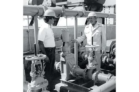 Black and white photo of two men working on disposable waste system