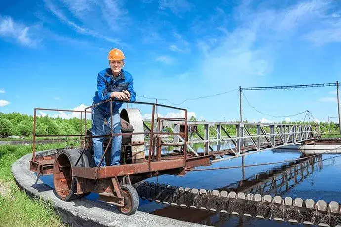 Senior worker standing on waste water treatment unit on plant