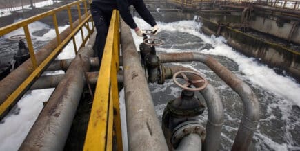 Workers oversee processes at an older wastewater treatment plant